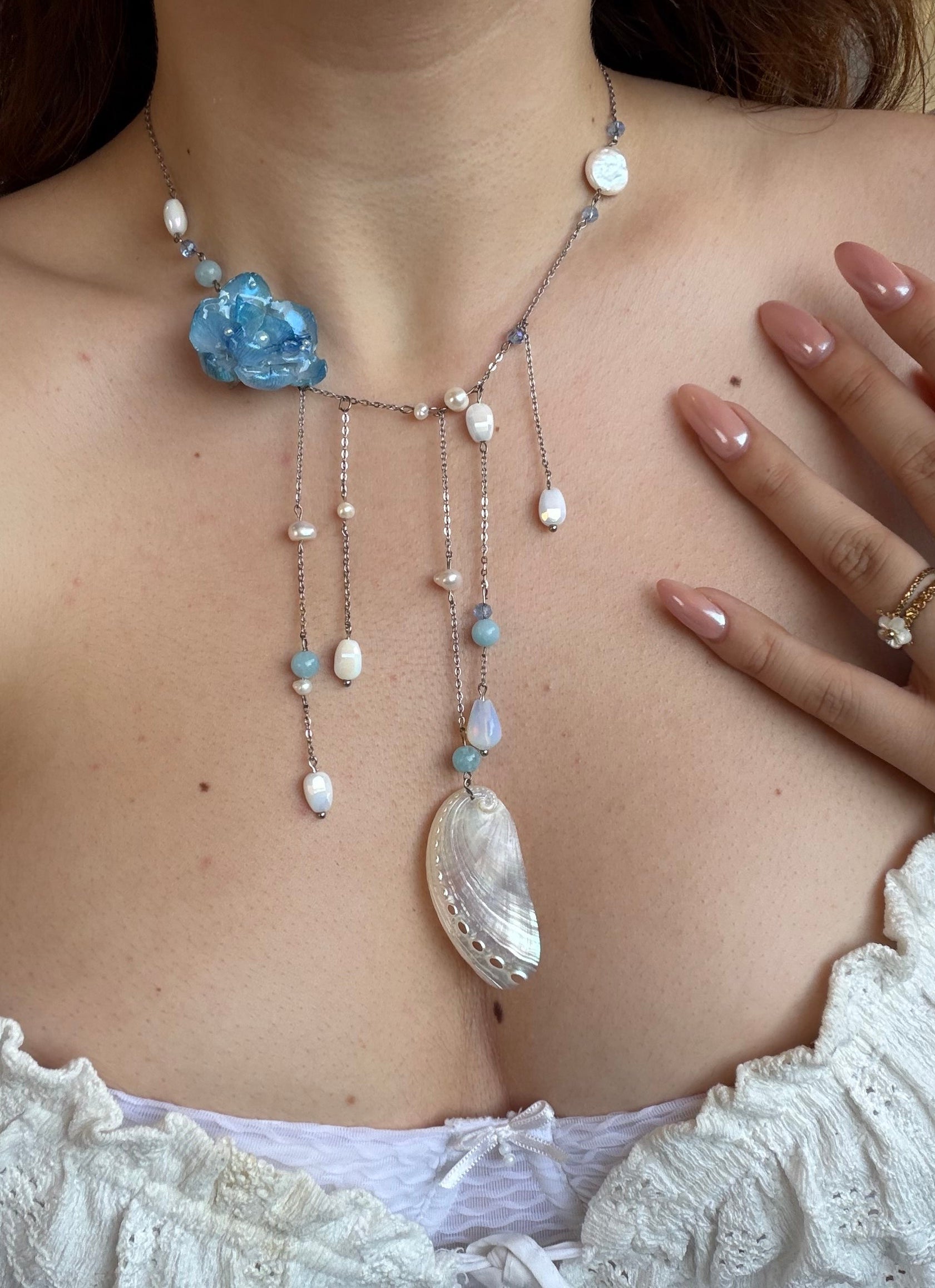 Close-up of a person wearing a decorative body chain with beads and a blue stone.