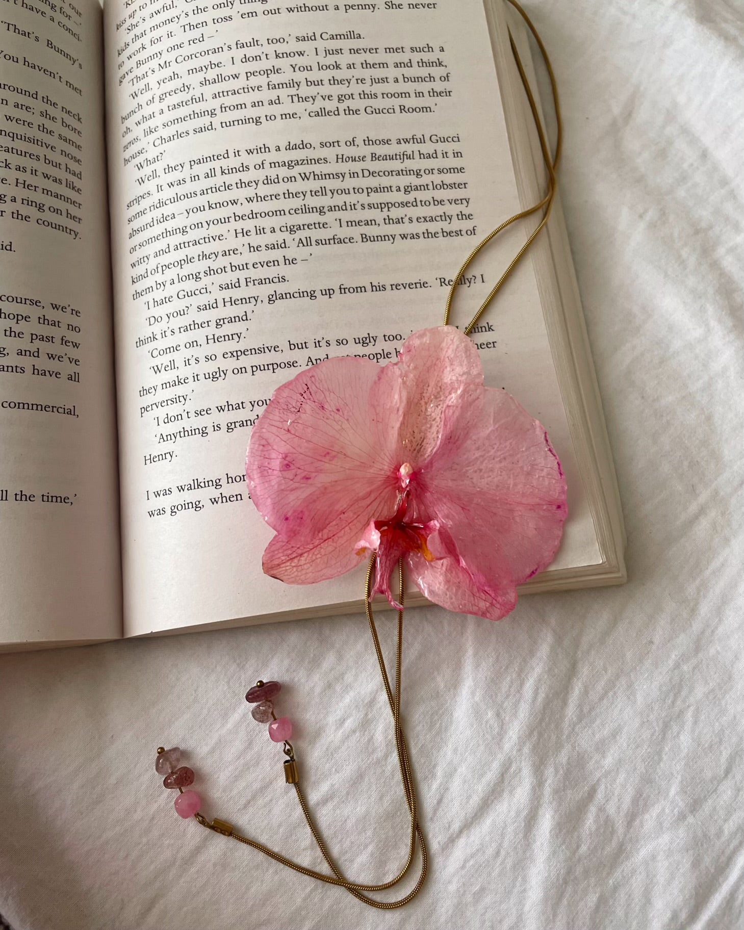 Pink flower bookmark on an open book with a white background
