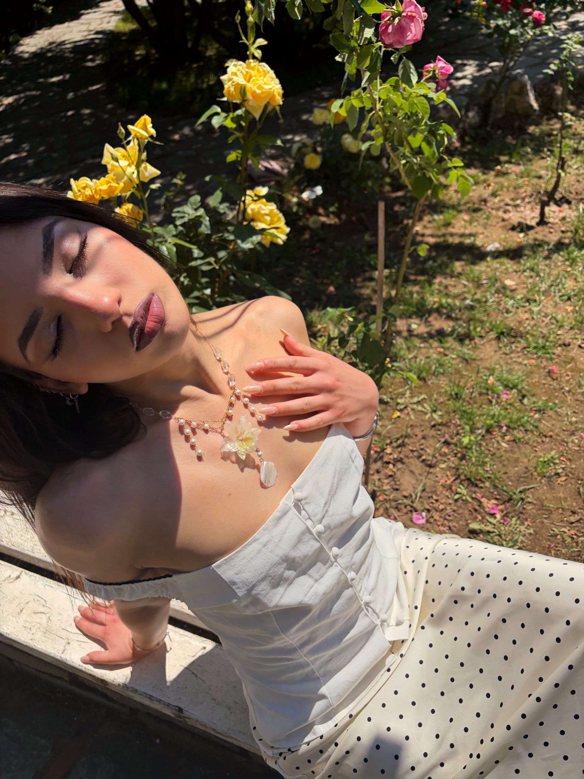 Woman lying on a stone bench with flowers in the background