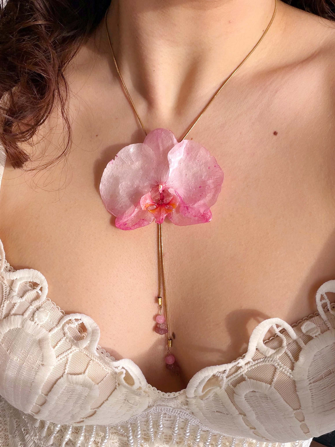 Pink flower pendant on a necklace against a blurred background